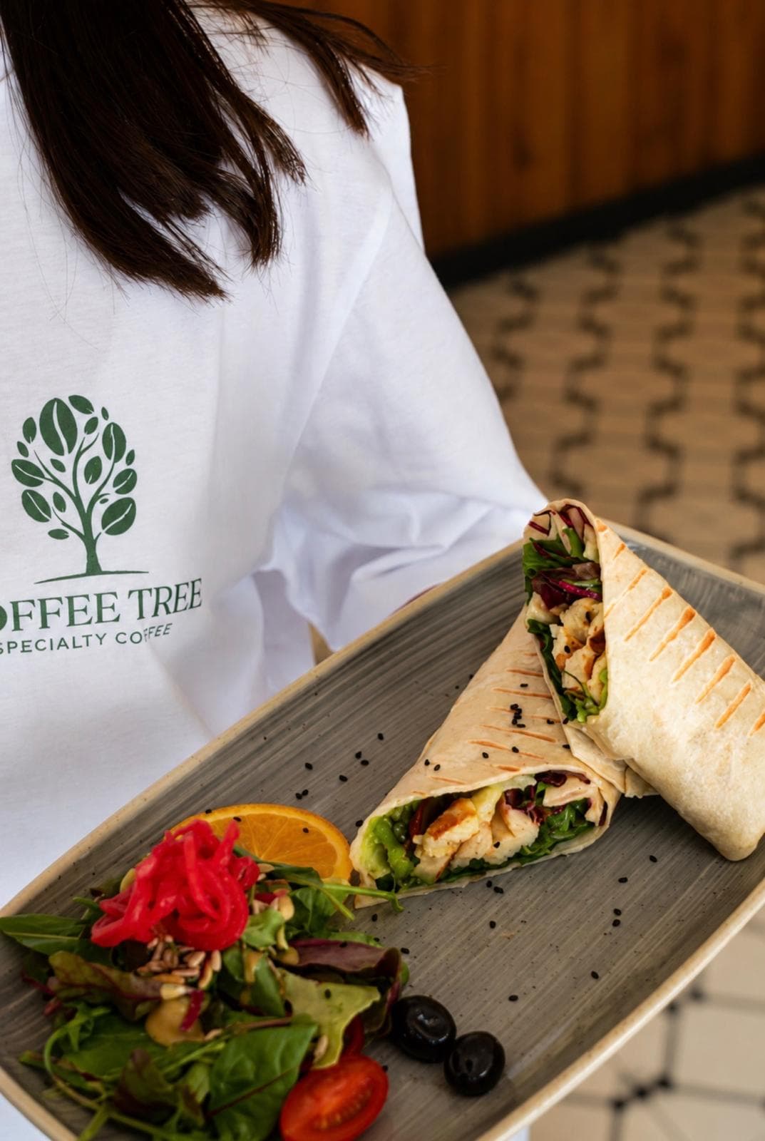 Mitarbeiterin im Coffee-Tree-Shirt mit einem Wrap auf einer Platte